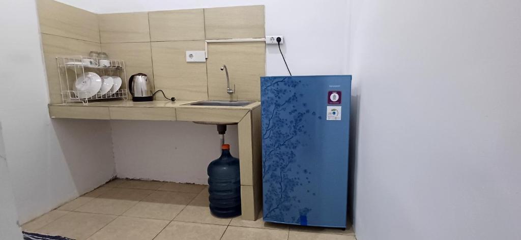 a small kitchen with a sink and a blue refrigerator at White Guest House in Sekongkang