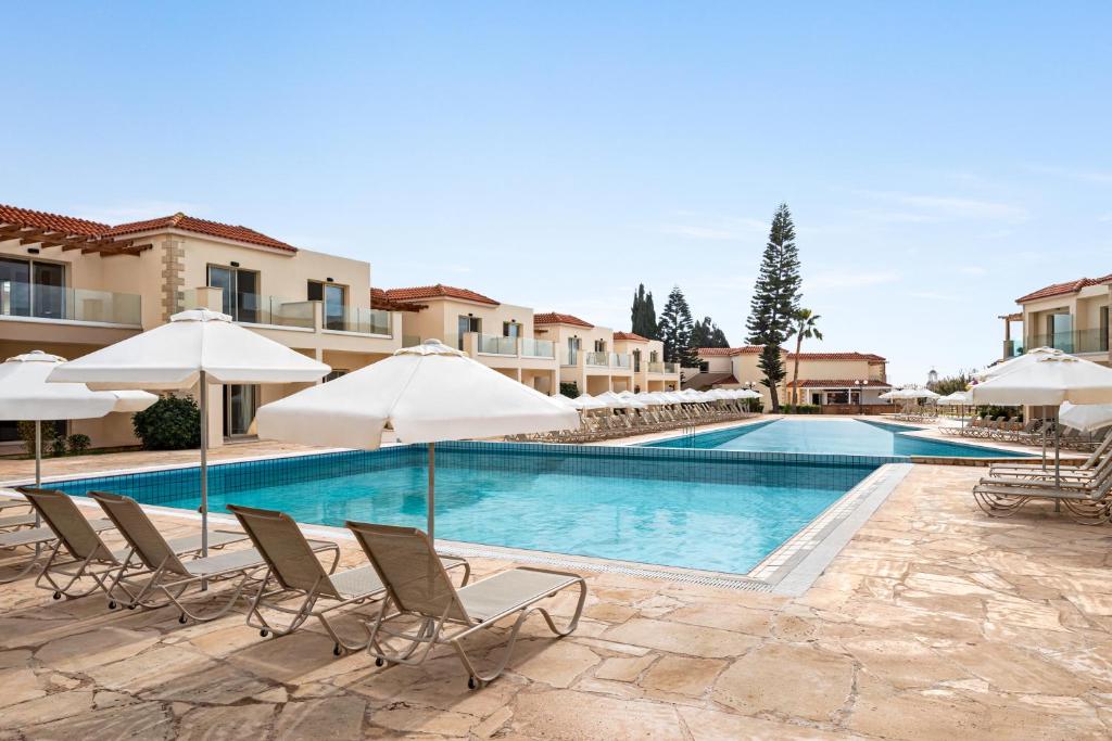 a swimming pool with lounge chairs and umbrellas at The Freij Resort in Ayia Napa