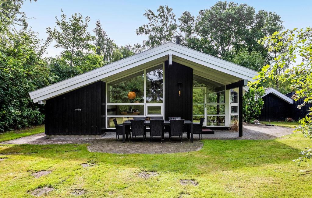 a black house with chairs and tables in the yard at Holiday Home Gyldenrisvej Denm in Skattebølle