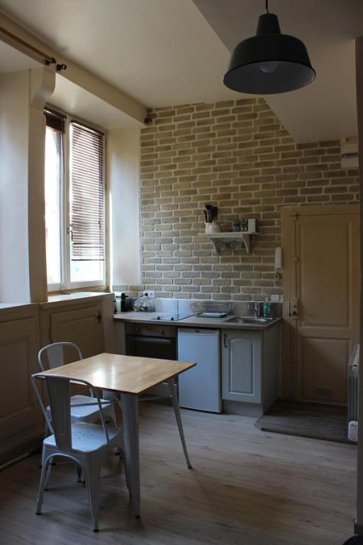 a kitchen with a table and a brick wall at Le Petit Beurre in Beaune