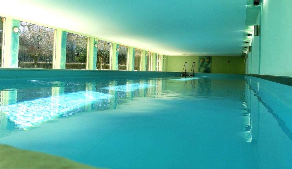 une grande piscine avec de l'eau bleue dans un immeuble dans l'établissement RENATE Haus KMB Seeappartement am Ossiacher See, Hallenbad, Skiarena Gerlitzen, à Bodensdorf
