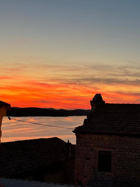 a sunset behind a building with a body of water at Bed & Breakfast The Konoba in Šibenik