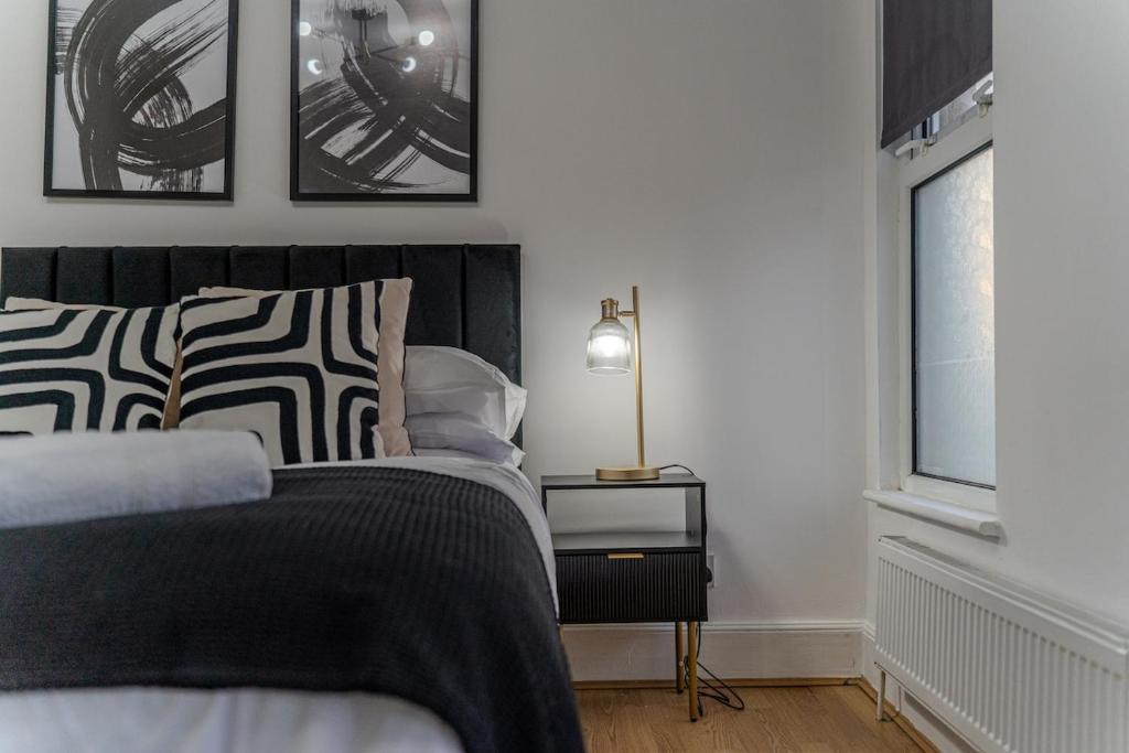 a bedroom with a bed with black and white pillows at The Hampden House - Sleeps 7 in Grays Thurrock