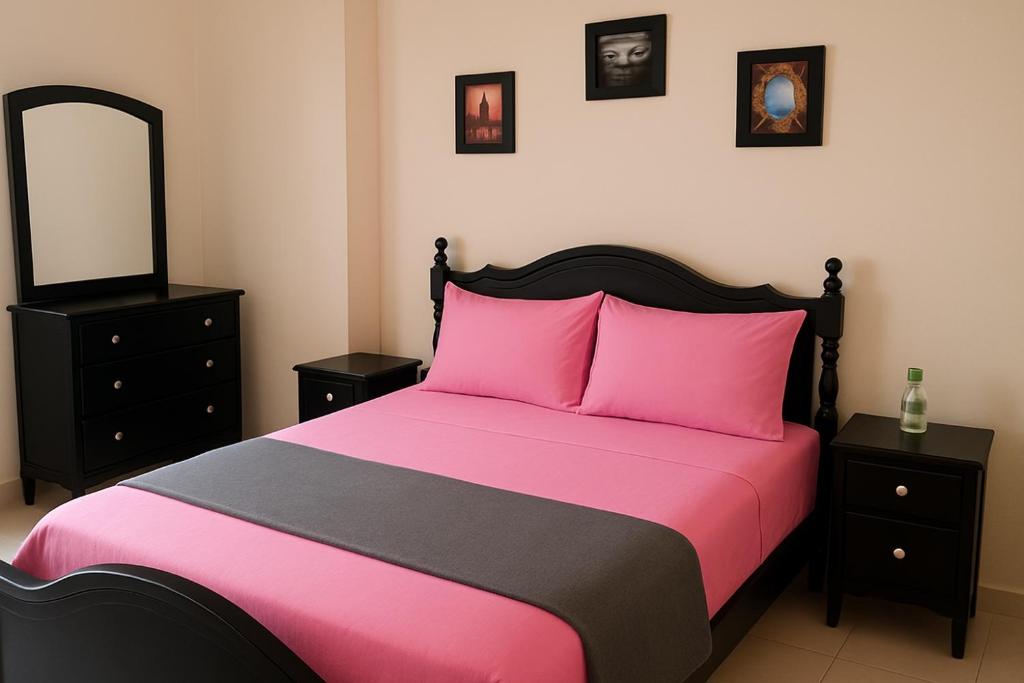 a bedroom with a pink bed and a mirror at Suit Home in Martil