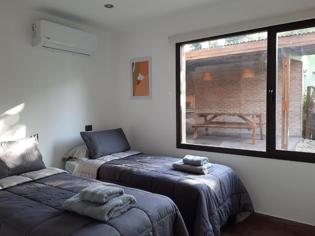 a bedroom with two beds and a large window at Casa Lavanda in Sierra de los Padres