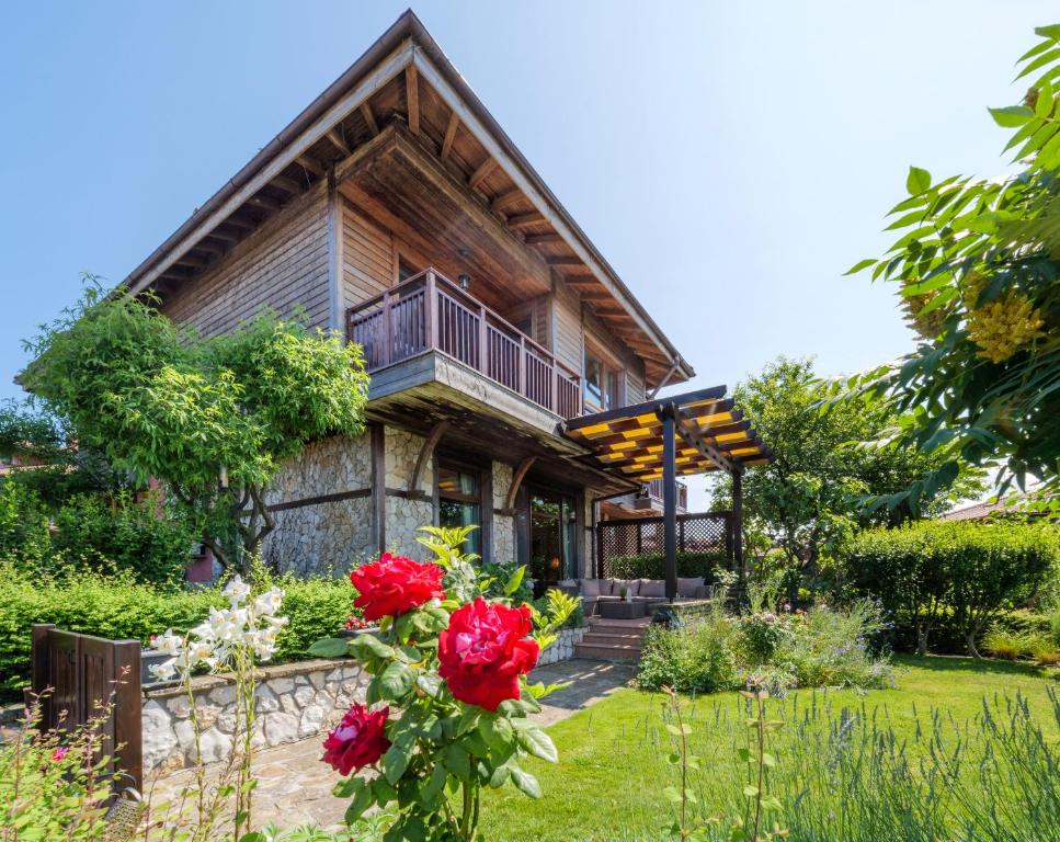 a log house with a balcony and red roses at Luxury 3-bedroom villa in Sozopolis with sea view in Sozopol