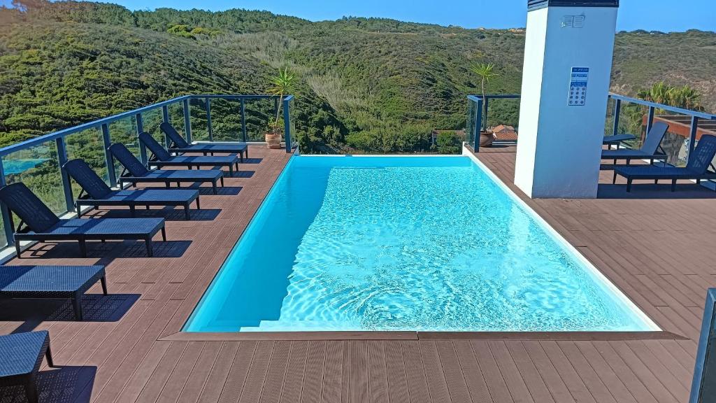 a swimming pool on a deck with lounge chairs at Zambujeiraseahouse - 100m da praia in Zambujeira do Mar
