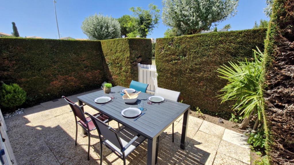 a table and chairs sitting on a patio at Vaux sur Mer - côté PONTAILLAC - VILLA MITOYENNE - PISCINE COLLECTIVE in Vaux-sur-Mer