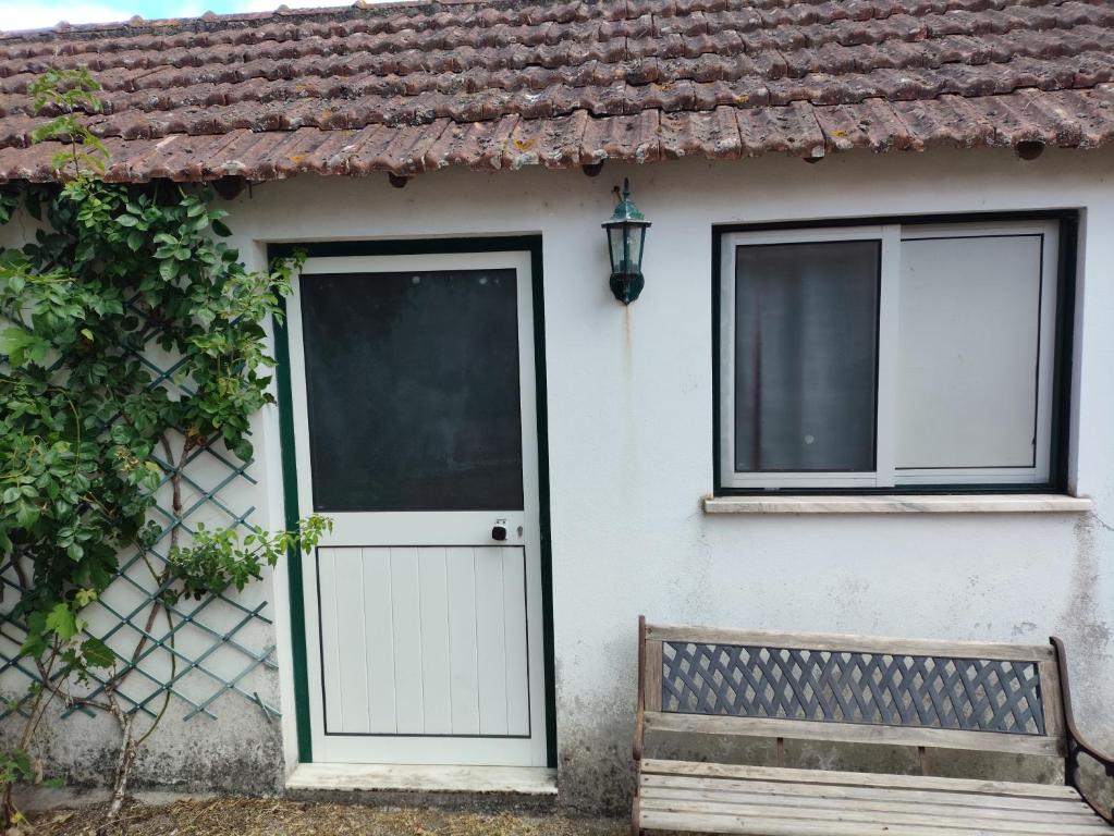 a white house with a door and a bench at Casinha da Lameira in Almagreira