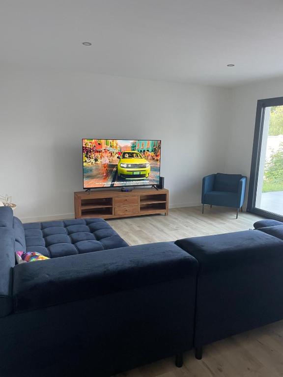 un salon avec un canapé bleu et une télévision à écran plat dans l'établissement Villa Détente, à Hourtin