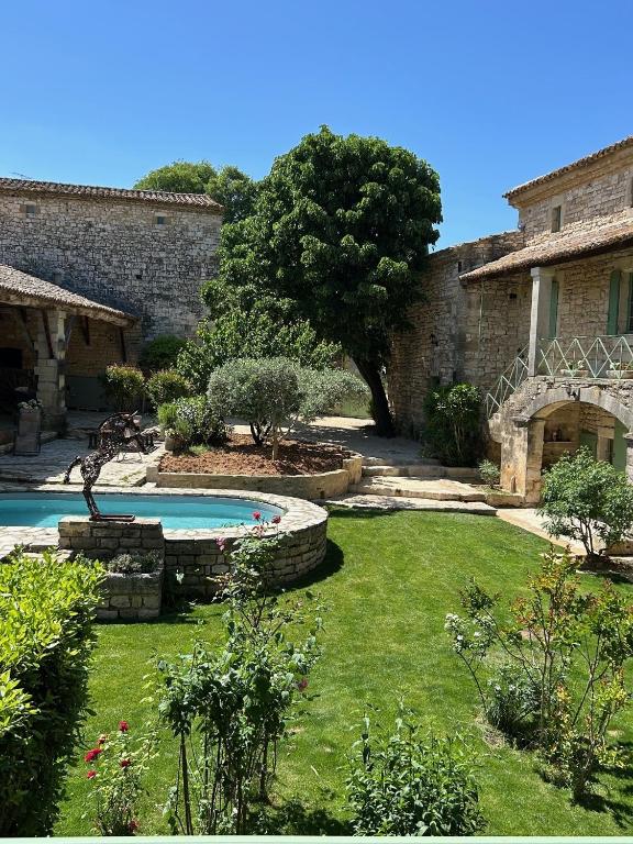 un jardin avec une piscine en face d'un bâtiment dans l'établissement Le mas de Brel, à Arpaillargues-et-Aureillac