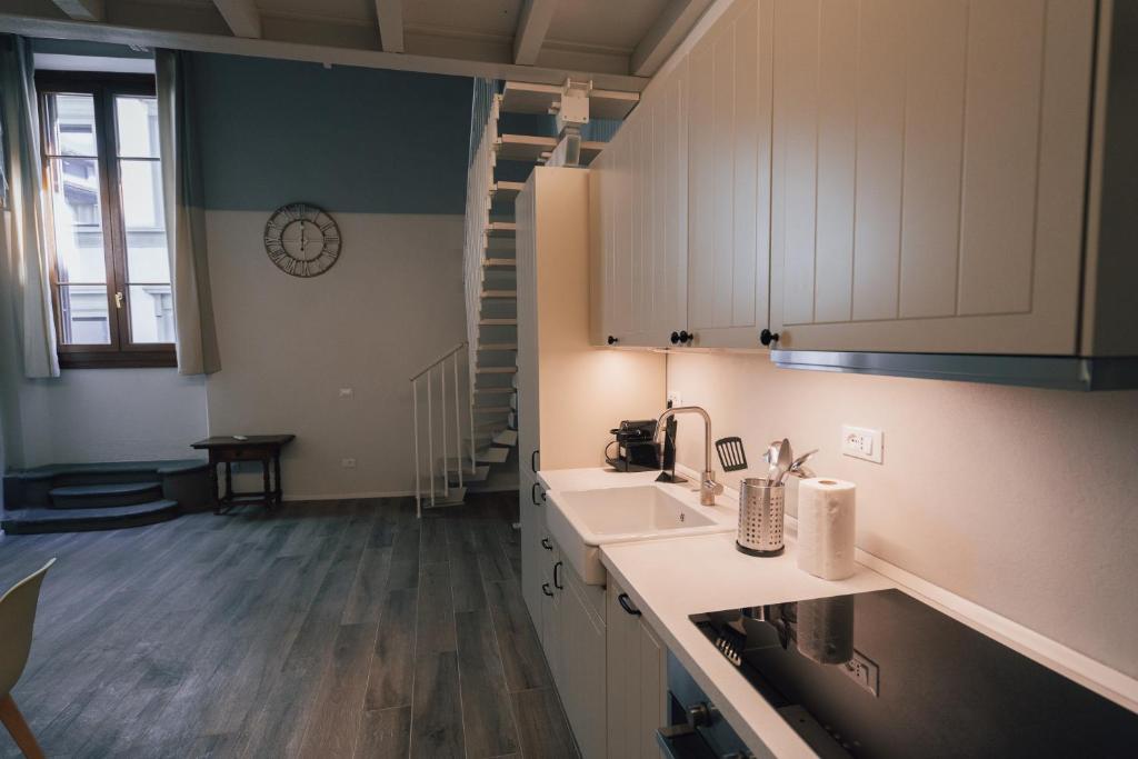 フィレンツェにあるPalazzo magnaleの白いキャビネットとシンクと階段付きのキッチンが備わります。