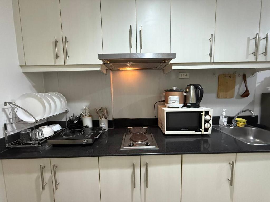 a kitchen with a counter top with a microwave at Sea Residences MOA Pasay City - Rose Staycation in Manila
