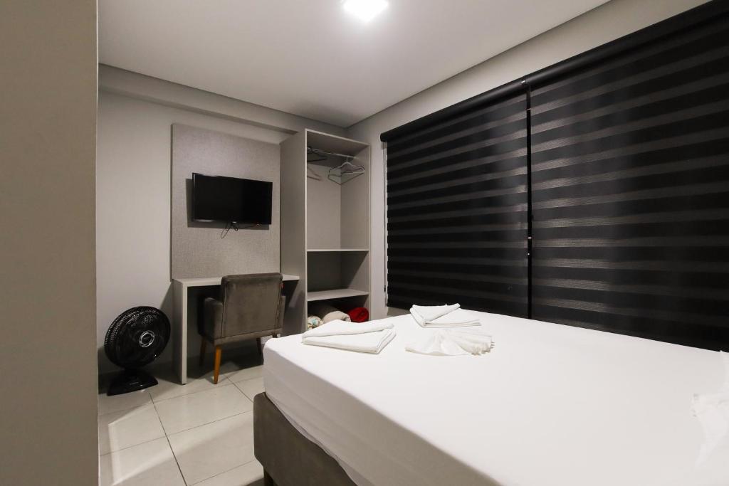 a hotel room with a bed and a television at Lou Suítes - Suíte 01 - Sonho e Descanso in Guarapuava