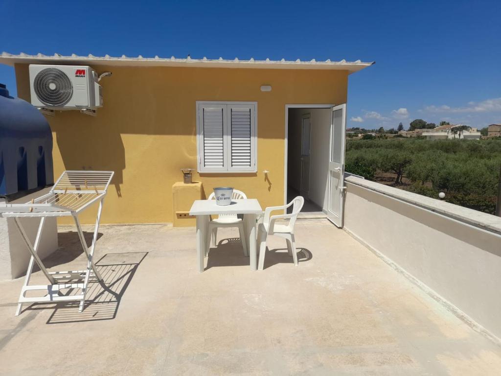 a patio with a white table and chairs on a roof at Villa Porto fossa 2 in Marzamemi