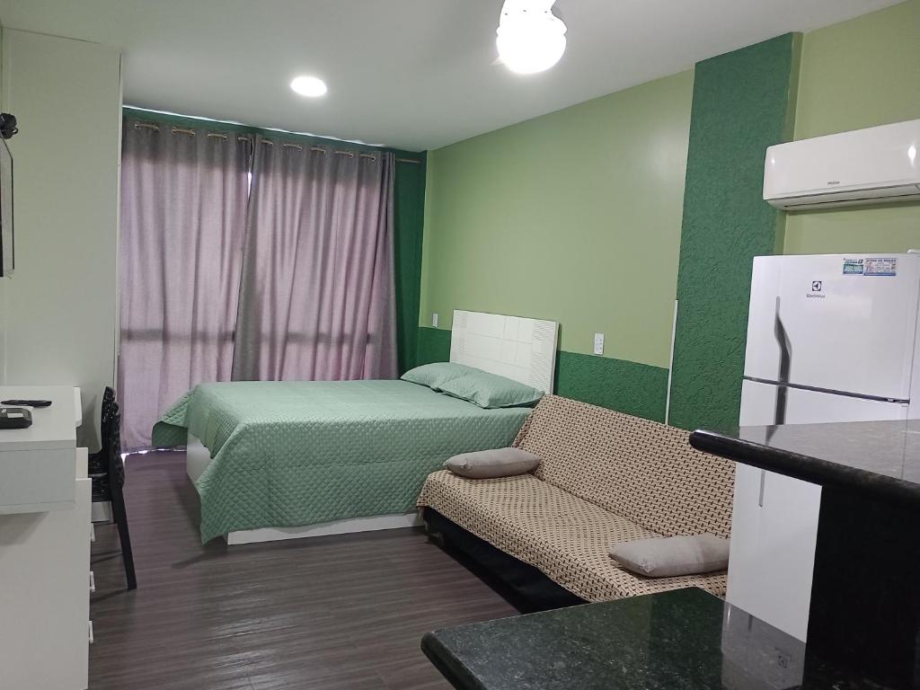um pequeno quarto com uma cama e uma geladeira em Loft Beira Mar Prainha wi-fi 600 megas apt 323 em Arraial do Cabo