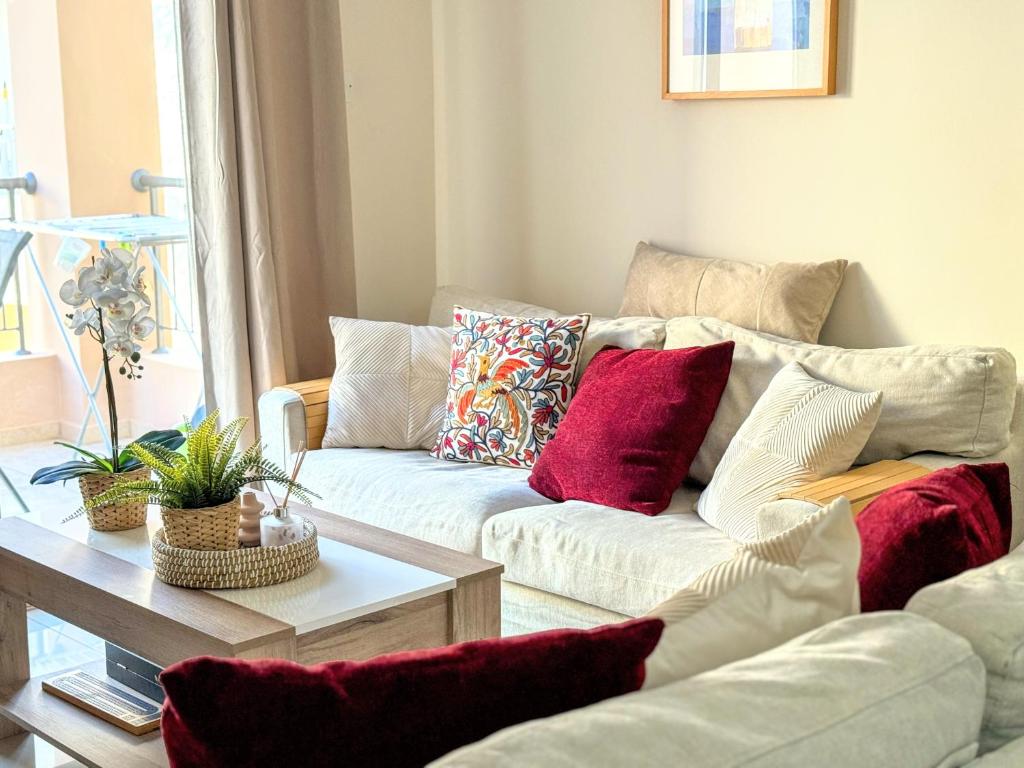 a living room with a white couch with red pillows at Comfy 1 bed Apartment, great location 200Mbps WiFi in Paphos City