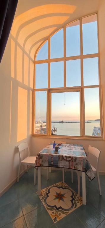 a table and chairs in a room with a large window at Casa MiraMare in Procida