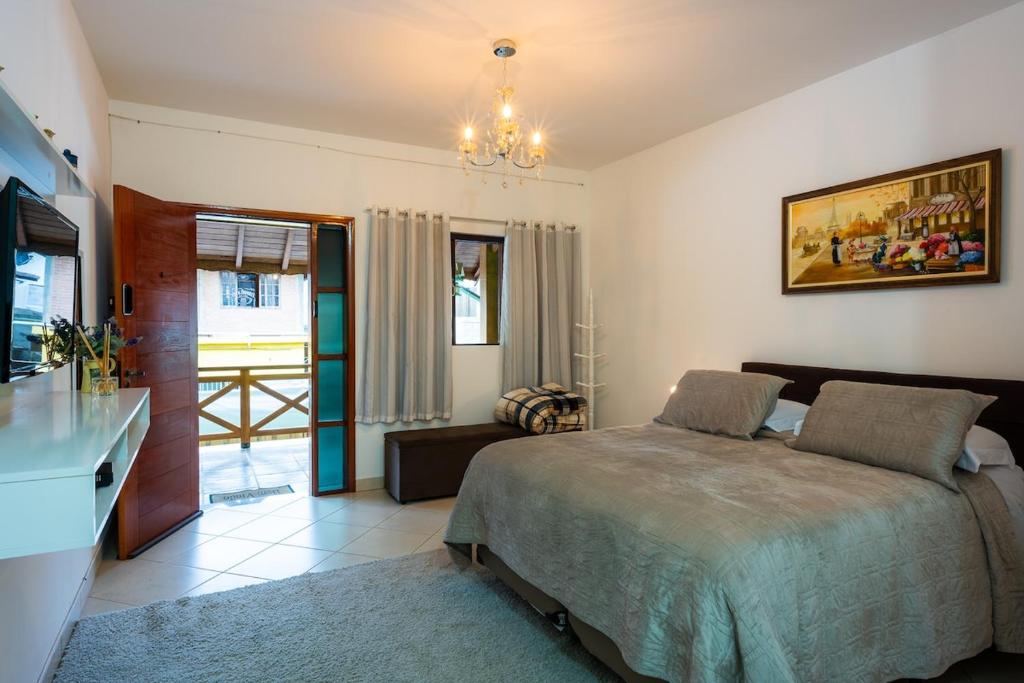 a bedroom with a bed and a chandelier at Apartamento Le Quatre Avenida in Monte Verde