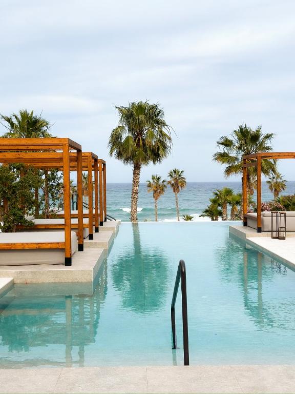 a swimming pool with palm trees and the ocean at Flamingo Mojácar - Precioso 2 dormitorios en Macenas Resort, con vistas al mar y piscina in Mojácar