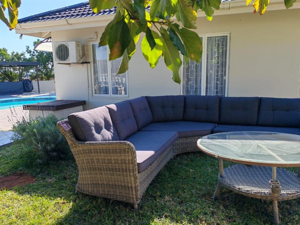 un divano blu e un tavolo di vetro nel cortile di Marula guest house a Durban