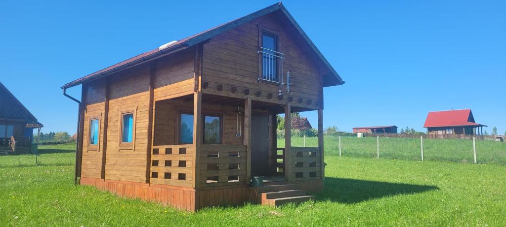 een klein houten huis in een grasveld bij Domek nad jeziorem Jan, Giże in Giże