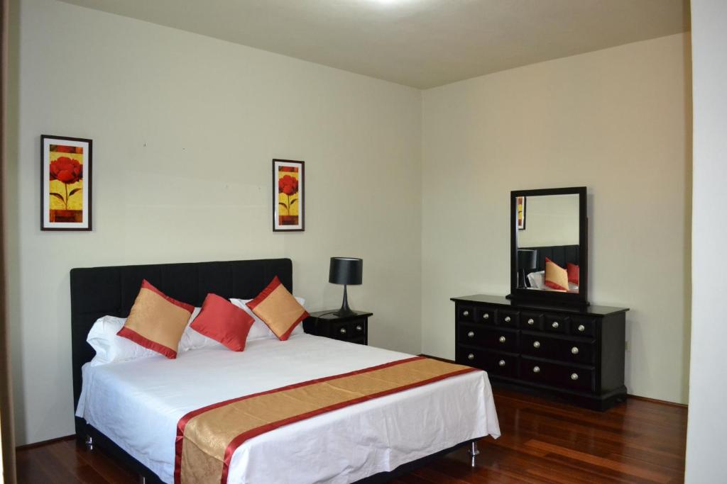 a bedroom with a large bed and a mirror at Negril Sky Blue Resorts LTD in Negril