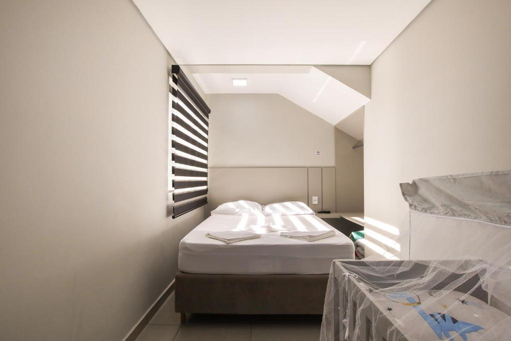 a small room with a bed and a window at Lou Suítes 2 - Conforto, Chique in Guarapuava