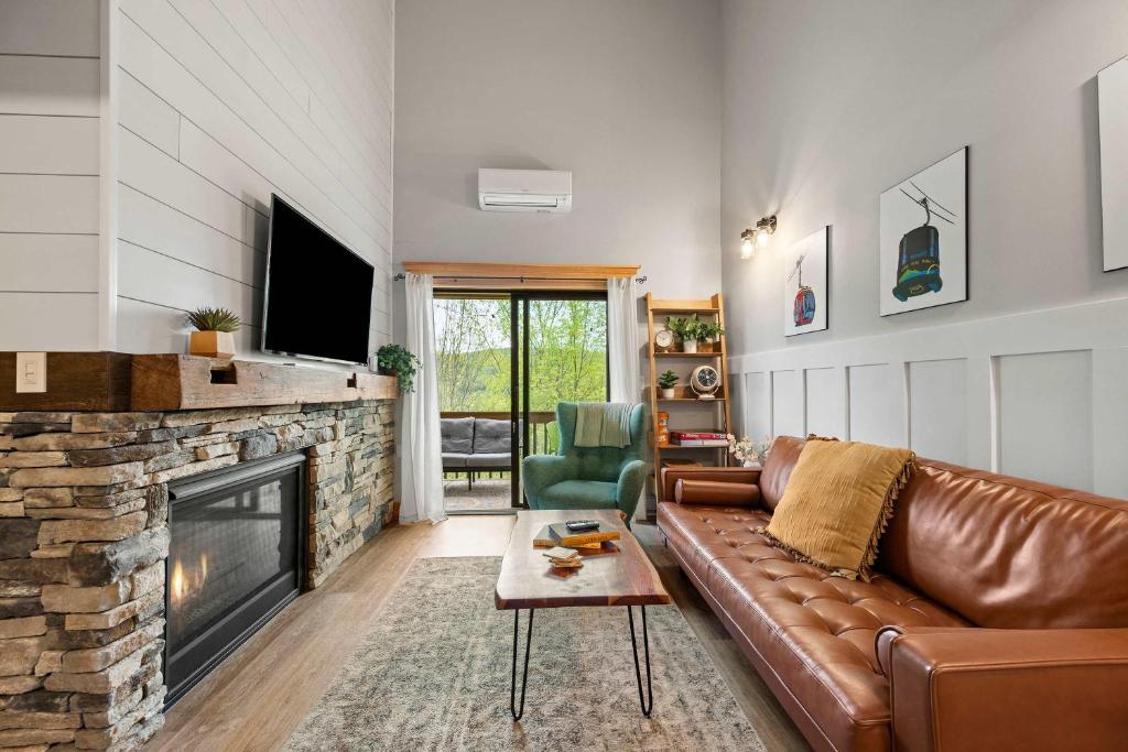 un salon avec un canapé en cuir et une cheminée dans l'établissement Renovated Ski In Out Condo King Bed Patio Grill, à Ellicottville