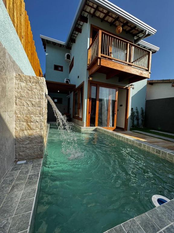 a swimming pool with a water feature in front of a house at Marlim-azul Loft in Prado