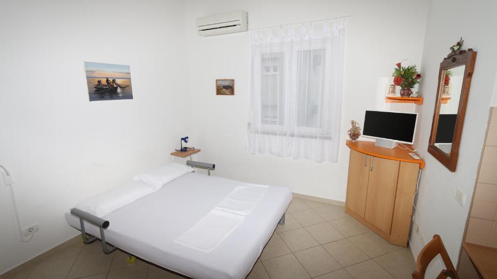 ein weißes Zimmer mit einem Bett und einem Fernseher in der Unterkunft Dugiš studio-no parking in Makarska