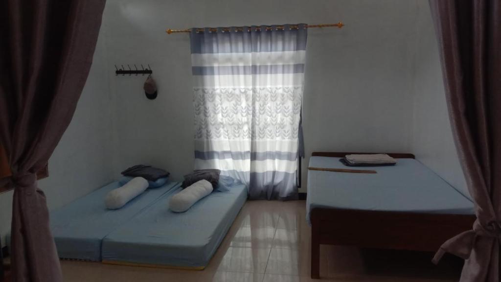 two beds in a room with a window at Naufal Homestay in Yogyakarta