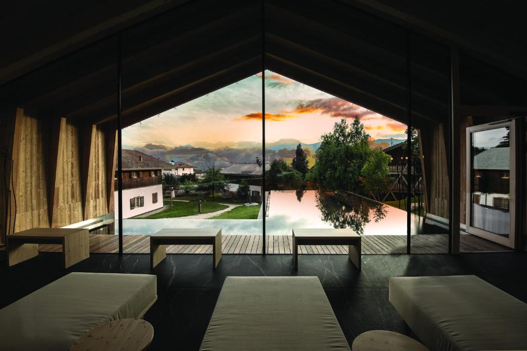 a room with a large window with a view at Pineta Nature Resort - Wellness & SPA in Coredo