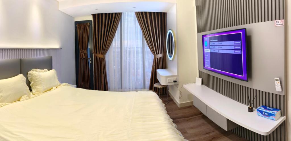 a bedroom with a bed and a tv on a wall at Pollux Habibie Batam Polux in Batam Center