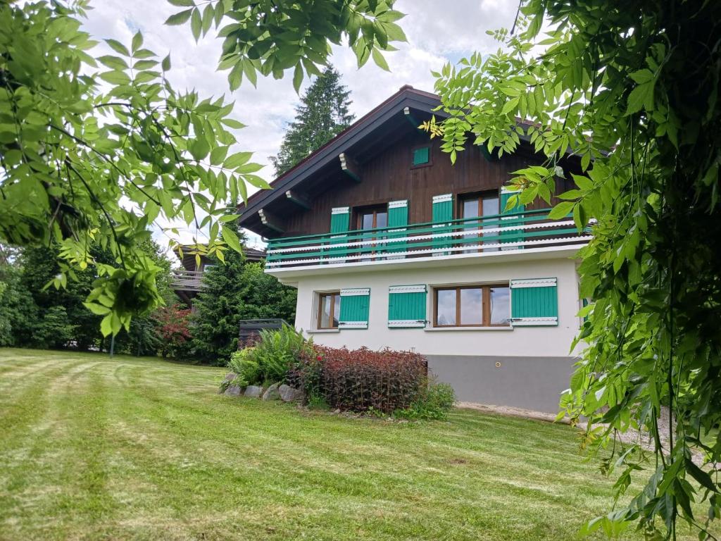 a white house with blue windows and a yard at Chalet Mireneige, charme et confort face au Mont Blanc in Combloux