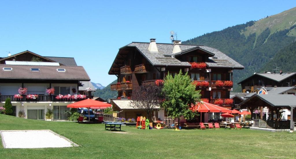 un grand bâtiment avec des parasols rouges devant lui dans l'établissement Résidence Frond'Neige, à Morzine