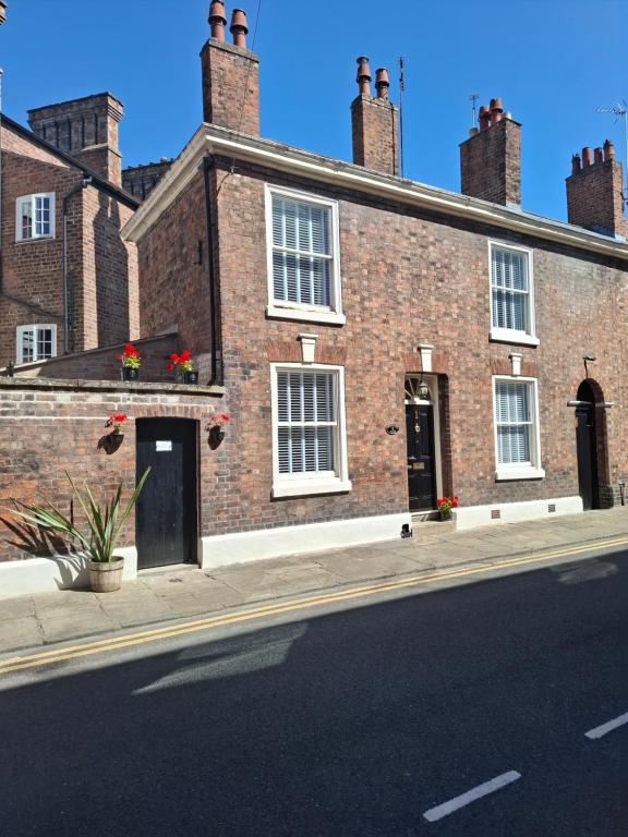 a brick building with white windows and red flowers at The Duke's Townhouse in Chester