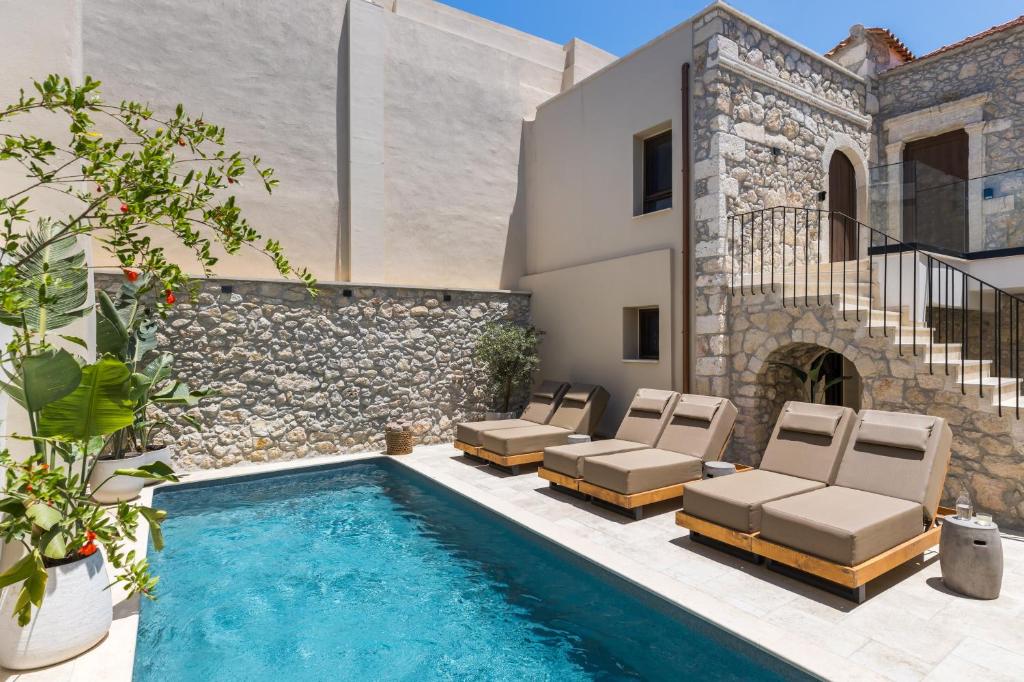 a pool with chaise lounge chairs and a house at Vernardo's Heritage by Nest in Gerani