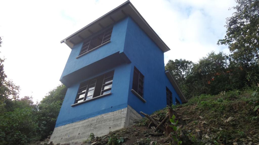 ein blaues Haus auf einem Hügel in der Unterkunft Blue Pine Farm Lodge Cabanas in Coroico