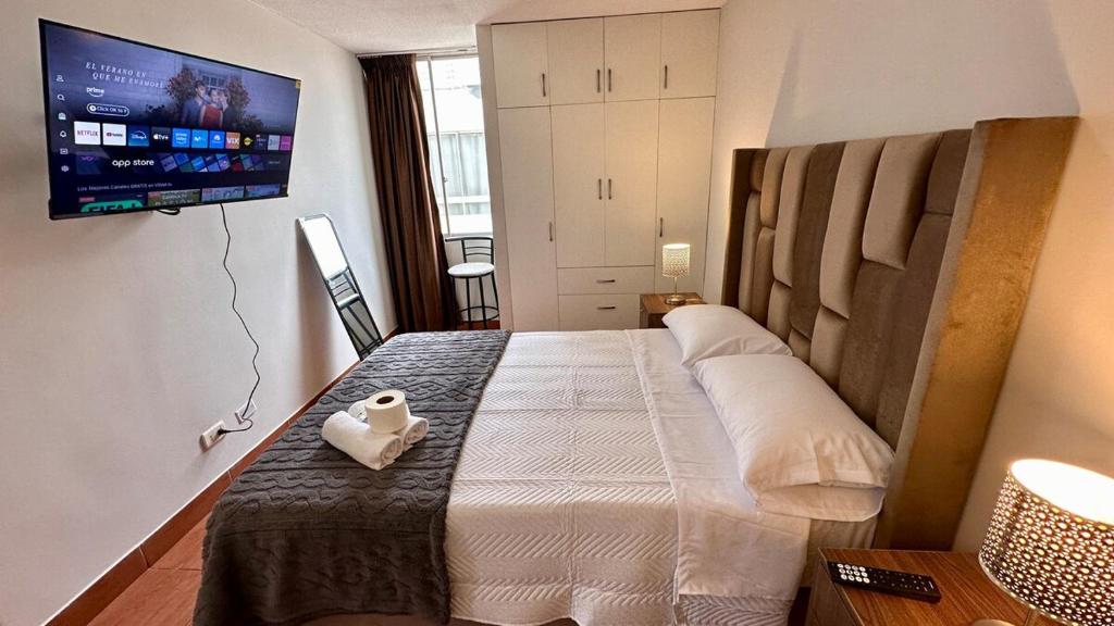 a bedroom with a large bed with a tv on the wall at Hermoso Departamento Frente al Escuela de Oficiales de La policia in Lima