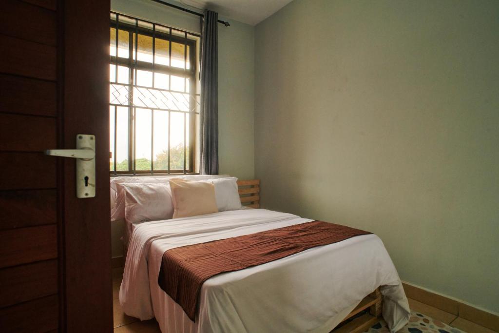 a small bedroom with a bed and a window at Bluezone Residence in Arusha
