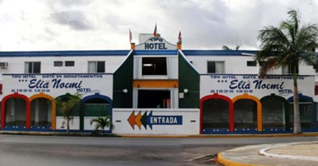 a white and blue building with a palm tree at Hotel Suites Elia Noemi in Mérida