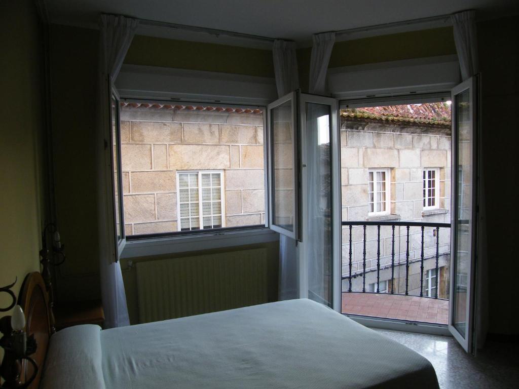 a bedroom with a window and a bed and a balcony at Hotel Bayona in Baiona