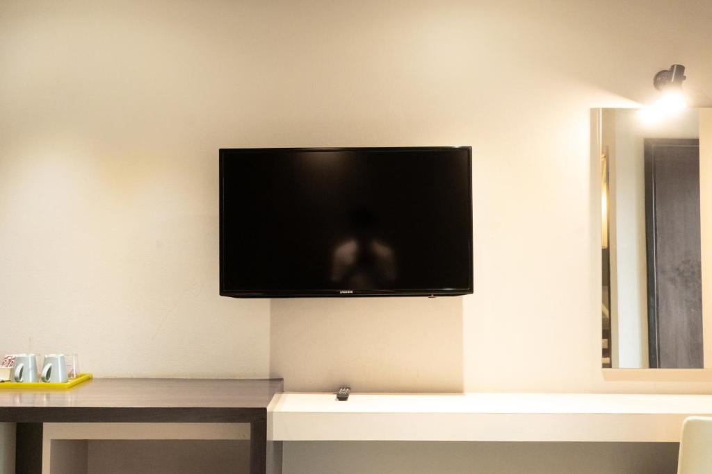 A wall-mounted television above a compact desk and beverage station.