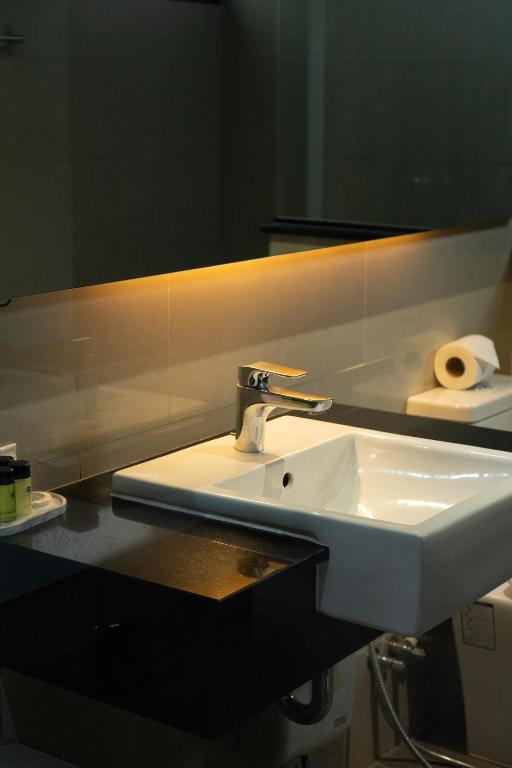 A contemporary bathroom vanity with a square basin and illuminated mirror.