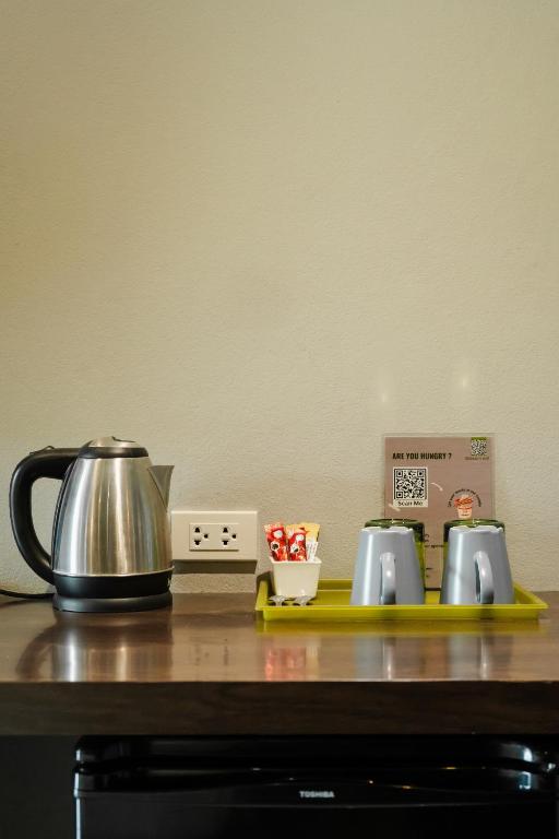 A beverage station with a kettle, cups, supplies, and a compact appliance below.