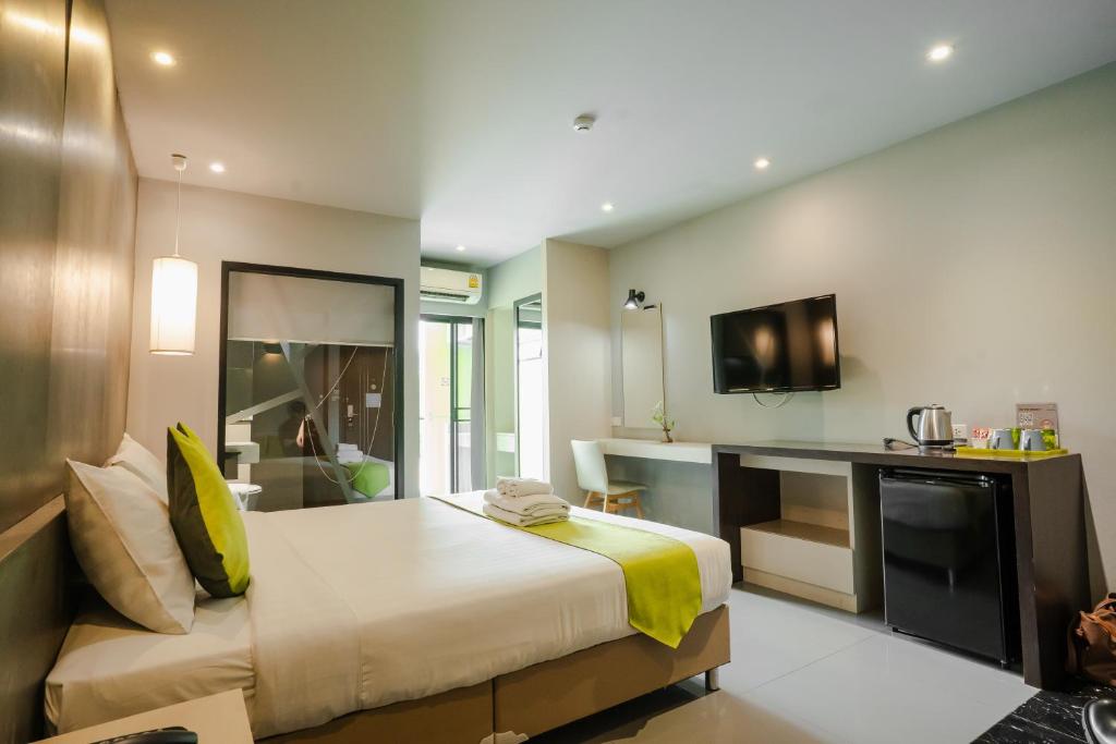 A spacious-looking bedroom with a large bed, desk, TV, minibar and bright window area.