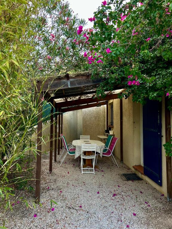 un patio avec une table et des chaises sous une pergola dans l'établissement Charmant bas de villa avec jardin, à La Ciotat