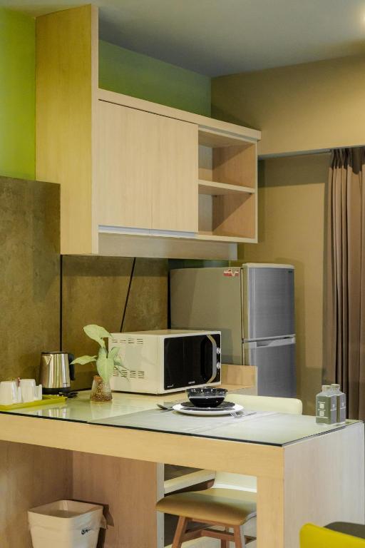 A kitchenette worktop provides a microwave, kettle, refrigerator and a small stool.