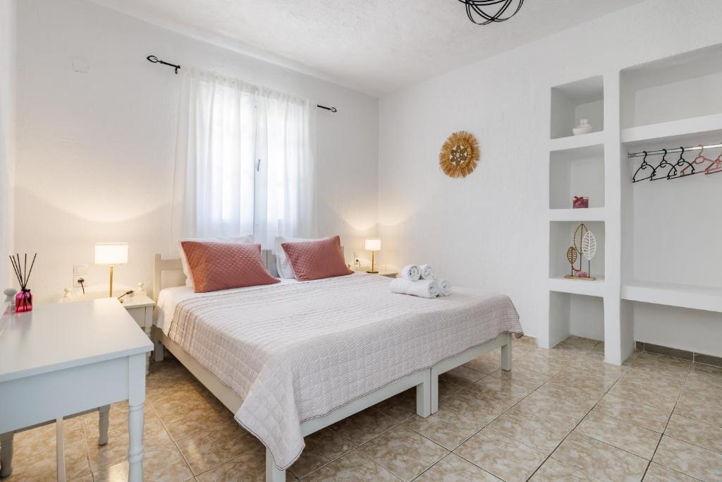 a white bedroom with a bed and a window at Aelia Apartment in Skopelos Town